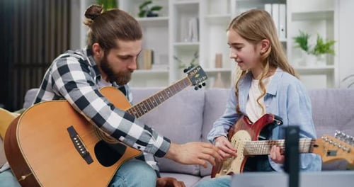 Man Teaches Child How to Play Guitar at Home