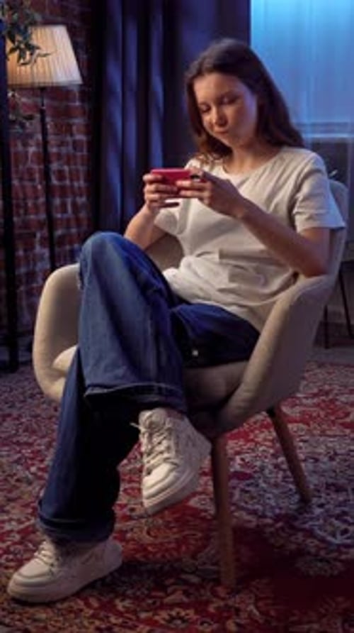 Young Woman Frustrated By Mobile Phone While Sitting in a Cozy Room