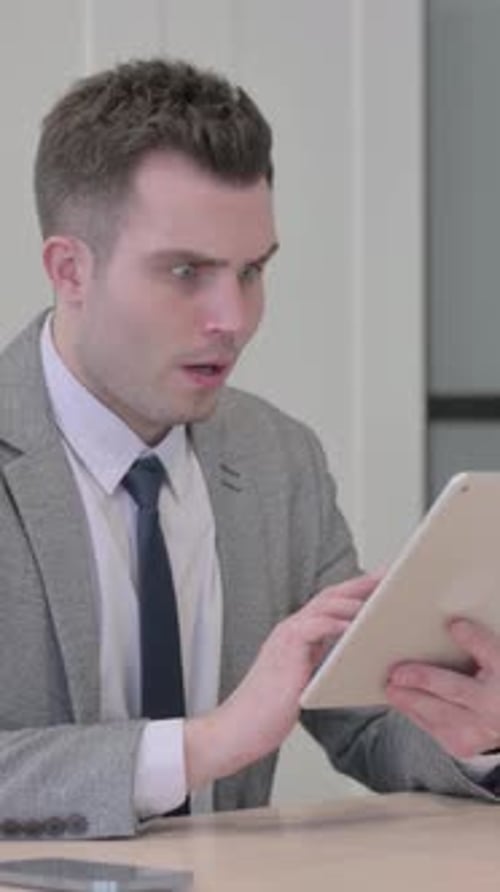 Excited Man Works on Tablet at Desk