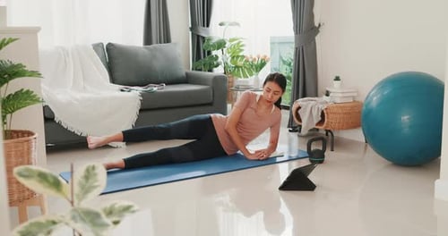 woman in sportswear watching fitness online video on tablet practice yoga for beginner.