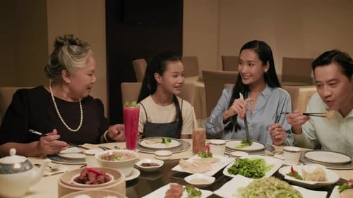 Members of Asian Family Talking while Eating in Trendy Cafe