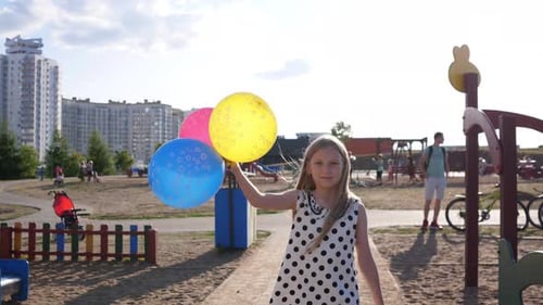 Cute Little Girl Walking with Balloons on the Playground