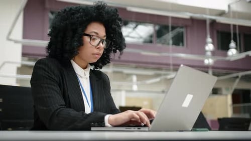 Professional Woman Typing on Laptop in Modern Office