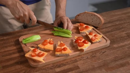 Man makes cheese sandwiches with cucumber and tomato