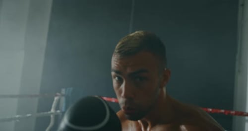 Cinematic slow motion shot of a professional young muscular shirtless man is practicing shadow box