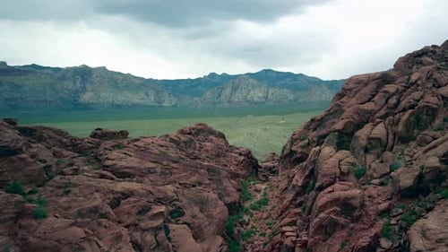 Aerial flying through a notch in Red Rock Canyon to reveal the valley below