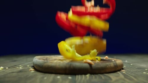 Sliced Bell Peppers Falling onto Wooden Cutting Board
