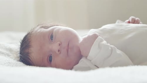 Innocent Newborn Baby Lying on a White Blanket