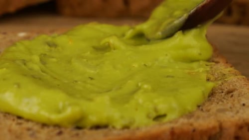 Le
guacamole est déposé sur un morceau de pain multigrains sur une planche à découper en bois. Nourriture pour végétaliens.