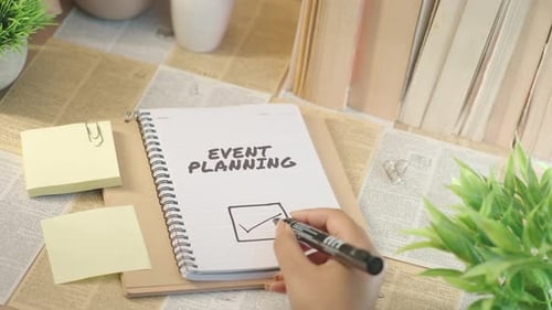 Hands Writing "Event Planning" in Notebook