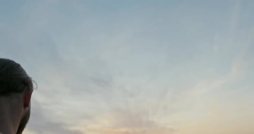 Man Raises Sword to Sky at Sunset