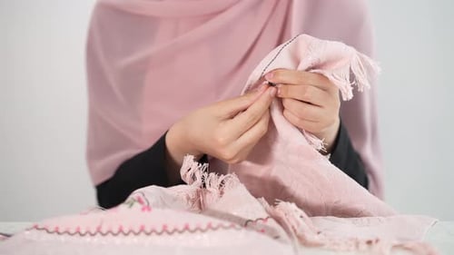 Woman Sewing Pink Fabric With Needle and Thread
