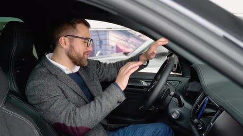 Happy Man Sits in New Car in Shop Dealership and Celebrate Purchase of New Vehicle