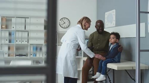 Mature Doctor Meeting Young Man and His Little Son in Medical Office