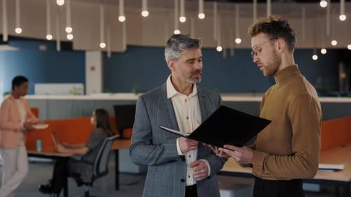 Dois parceiros de negócios segurando uma pasta com documentos se comunicam antes da reunião discutem o relatório interno