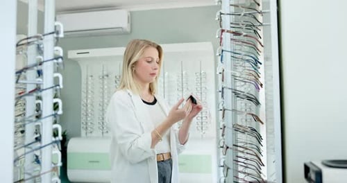 Optometrist, woman and cleaning glasses at shop with cloth for dust on lenses or frame and vision