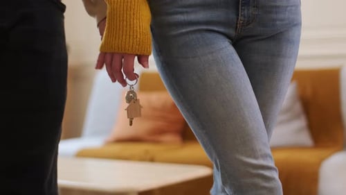 A Man Holds the Hand of a Woman Who is Holding the House Keys - Close Up