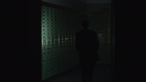 Man Searches Safe Deposit Boxes with Flashlight at Night