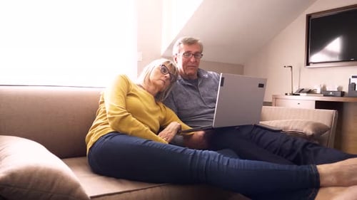 Couple Looking At Laptop On Sofa In Hotel Room
