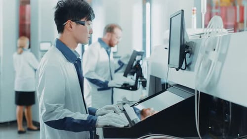 In einer High-Tech-Fabrik verwendet ein asiatischer Ingenieur einen Computer zur Programmierung von Elektronisch Pick-and-Place-Maschinen
