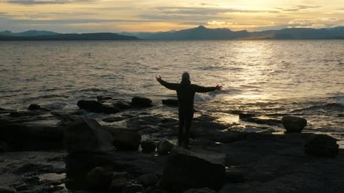 Silhouette Of Man Looking At The Sea While Raising His Arms