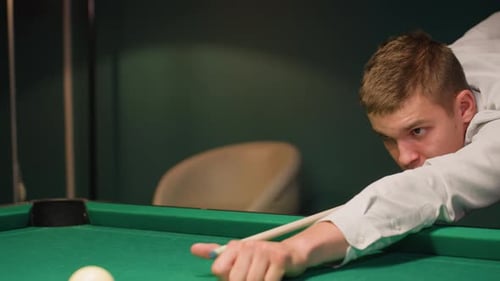 Man Playing Pool in a Dimly Lit Room