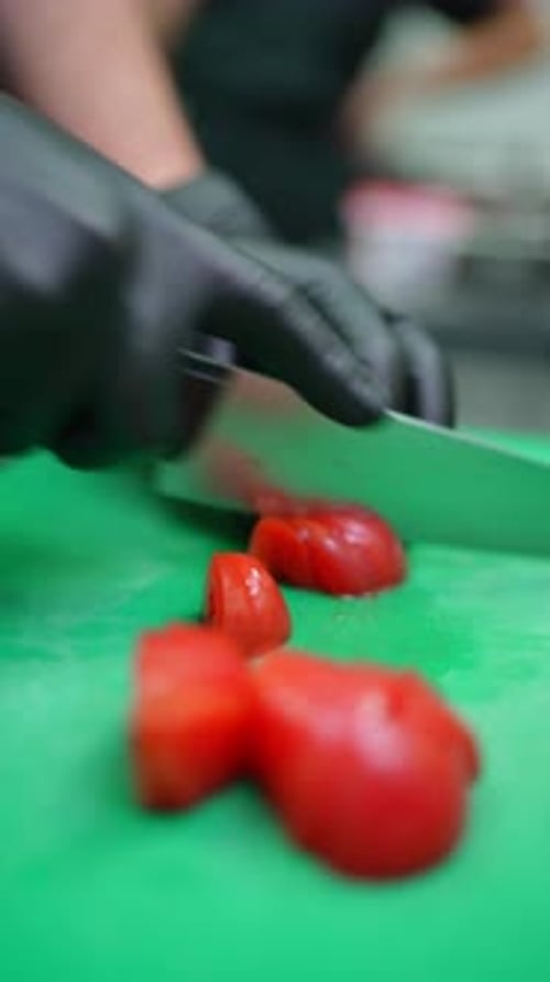 Professional Chef in Black Gloves Slicing Ripe Red Tomatoes on Green Cutting Board with Sharp Knife