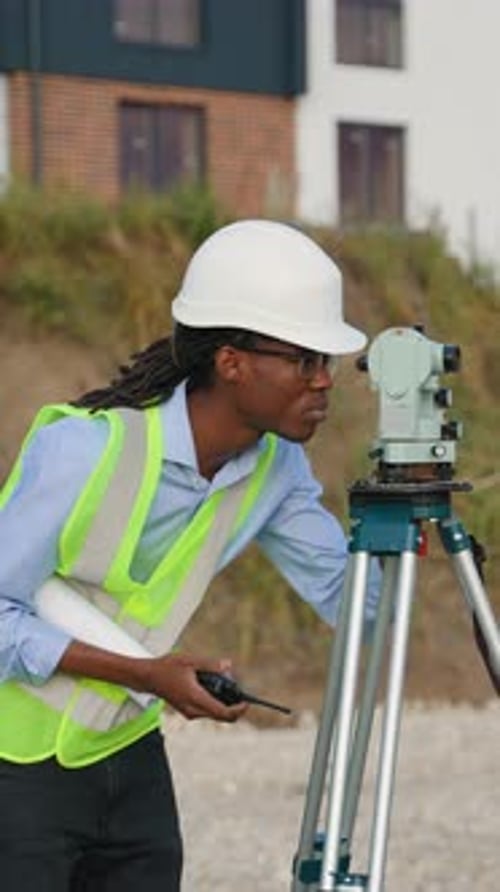 Construction Worker Using Theodolite and Walkie Talkie on Site