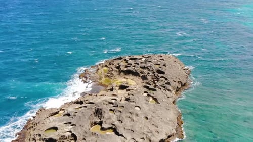 Aerial footage of a rock formation near the beach flying backwards.