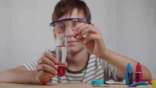 Niño deja caer la tableta en un tubo de ensayo con líquido rojo