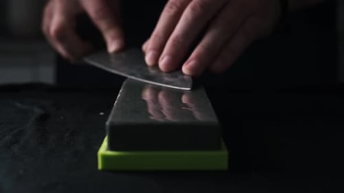 Male Hands Sharpening Kitchen Knife With Whetstone