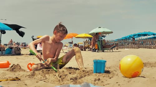 Boy Plays with Sand on the Beach