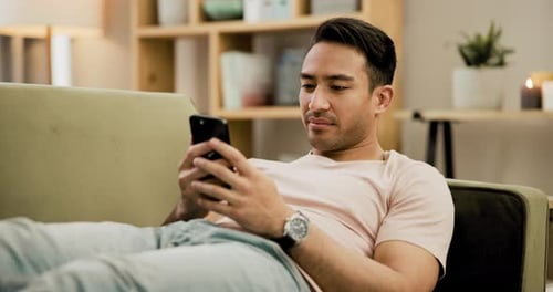 Young Adult Relaxing on Sofa with Phone