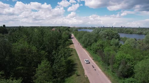 Top View of the Road Among the Trees with the Car and the Panorama of the Countryside with Lakes and
