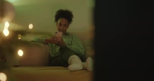 Woman Relaxing on Couch Using Phone at Night