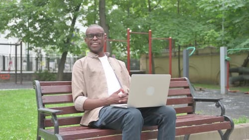 Man Working on Laptop in Park on Bench