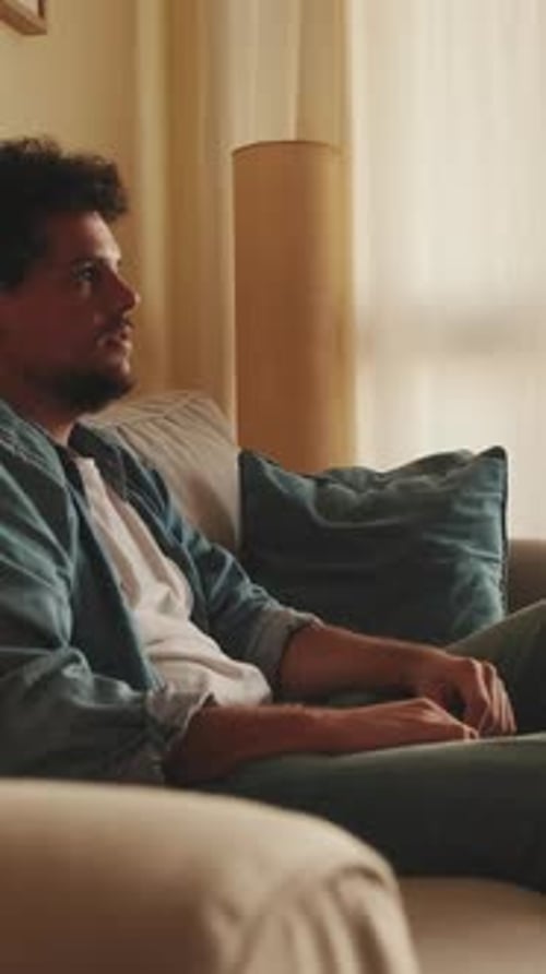 Young Adult Sitting on Couch Reacting