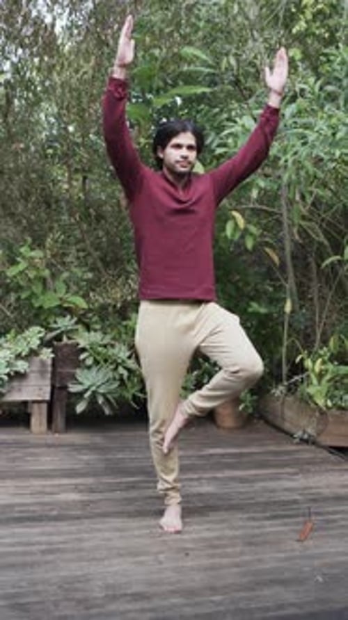 Vertical video of biracial man practicing yoga on terrace in nature, slow motion