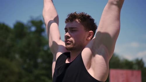 portrait of a young sweaty sportsman doing horizontal bar swings arms and shoulders push-ups