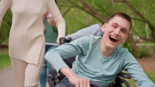 Cheerful Young Man in Wheelchair Enjoys Park Stroll