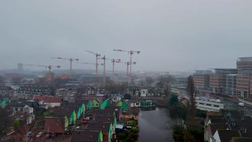 Construction activity in a developing urban area with cranes and fog in the background