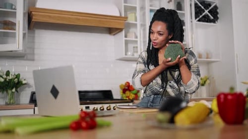 Mujer bloguera gastronómica graba un vídeo para un blog mostrando brócoli a una nutricionista femenina con cámara web