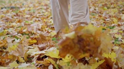 Close Up Feet in White Boots Walk on the Autumn Foliage with Golden Leaves