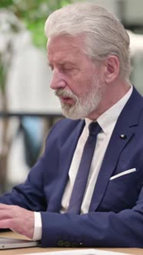 Senior Businessman Working on Laptop and Looking Up