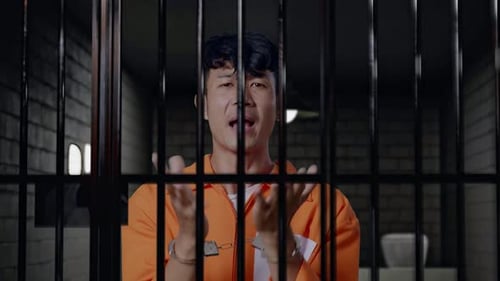 Close Up Of A Wondering Prisoner Doubtfully In Prison, Raising Hands In Anger And Shouting Why