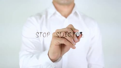 Man Writing 'Stop Suicide' on Transparent Surface