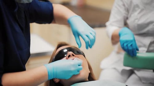 Tooth Whitening in Modern Stomatology Clinic Female Patient and Doctors Preparing Teeth for