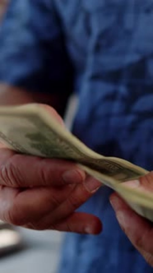 Man counting United States currency, one hundred dollar bills