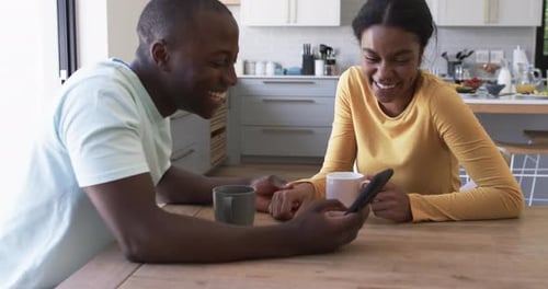 Happy Couple Using Phone Together at Table