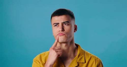 Man, thinking or ponder with question in deep thought for choice or decision on a blue studio